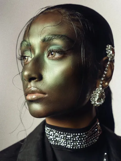 A profile view from the 'Chrome' beauty story. This angle highlights the flawless, metallic finish of the makeup and the elegant line of the model's neck and jaw.
