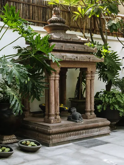 A miniaturized replica of a temple from Bhubaneshwar's Lingaraj Temple, placed within the courtyard. This, along with other traditional vessels repurposed as planters, adds character and a sense of sacred history to the space.