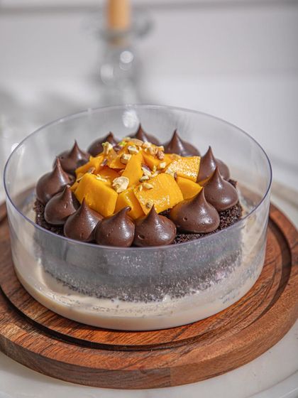 A close-up of our Mango Chocolate Tres Leches, showing the rich chocolate piping and fresh mango pieces.
