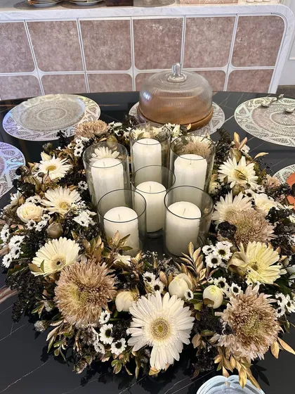 A beautiful floral wreath centerpiece designed for a dinner party table. I surrounded glass hurricane vases and candles with a mix of white and gold-dusted chrysanthemums and daisies.