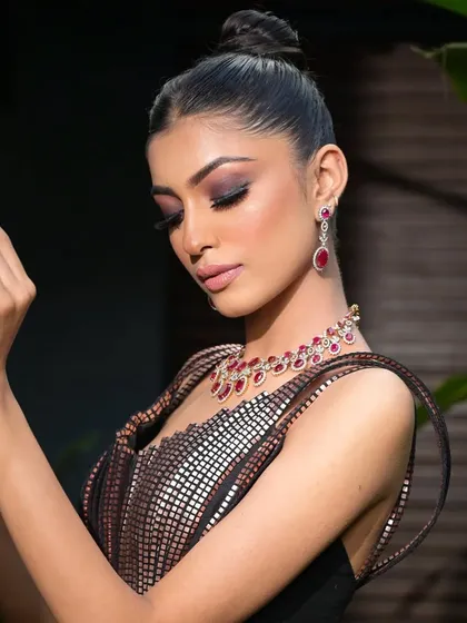 A portrait showing the high bun from the front. The severe, pulled-back style emphasizes the model's bone structure and the dramatic makeup.