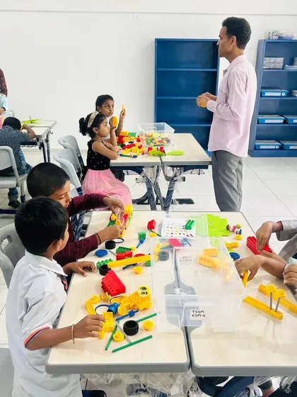 An instructor oversees a bustling classroom at The School for Global Minds, where young students are busy with their LEGO Education kits.