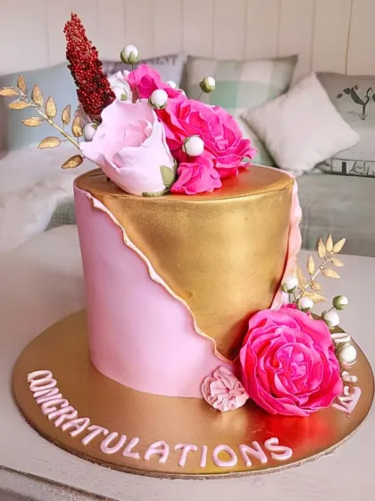 A modern and chic cake with a gold-leaf fault line design, accented with vibrant pink handmade sugar flowers.