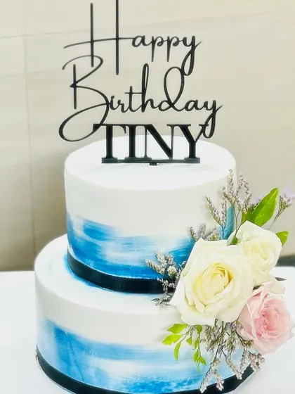 The full view of the two-tier blue watercolor cake with a custom "Tiny" topper.