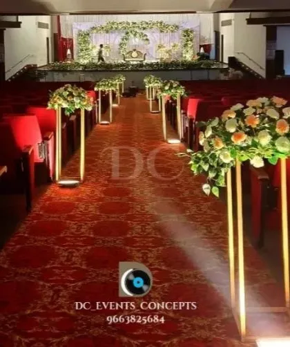 A view down the aisle of a large auditorium, with the pathway lined by our elegant floral stands. This shows how we decorate the entire guest journey, not just the stage.