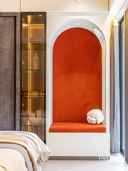 A detailed shot of the illuminated reading nook. The vibrant orange corduroy upholstery and a whimsical knot pillow make this arched alcove an irresistible spot for any child to curl up with a book.