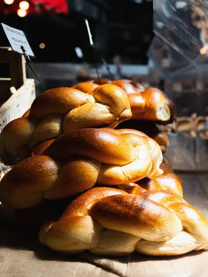 Freshly baked Challah bread at Borough Market. The natural light highlights the golden crust, making it a perfect shot for a bakery's online store or menu.