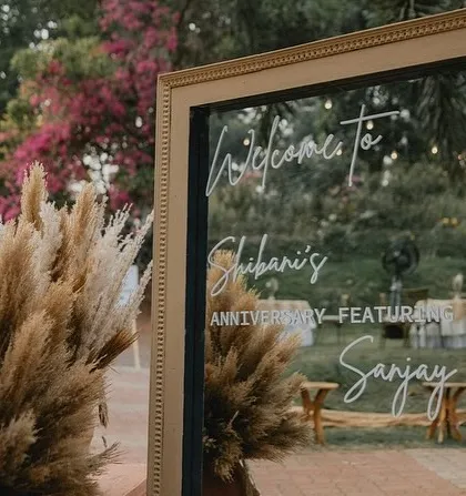 A personalized welcome sign for a 25th anniversary party. The elegant mirror sign, set against a backdrop of pampas grass, sets a sophisticated tone for the celebration.