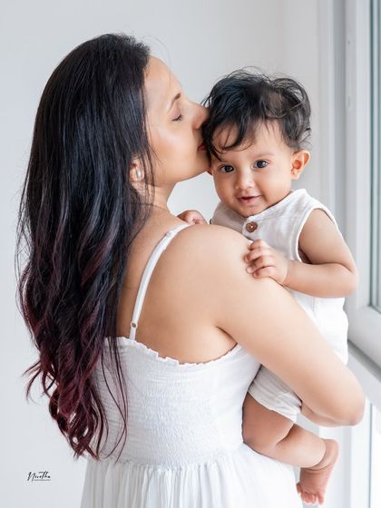 A mother holding her baby, who is looking at the camera.