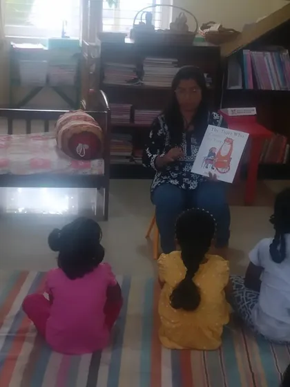 The children are seated comfortably on a striped mat, a signature feature of our cozy reading space, as they listen to a story.