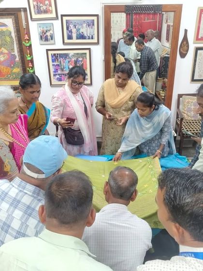 Showing a group of visitors a hand-embroidered textile. My studio is an open house for anyone interested in learning about or purchasing handmade crafts.