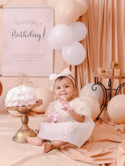 A beautiful, elegant first birthday setup with a neutral color palette. This little one is already enjoying her cake.