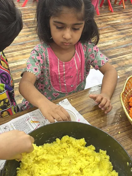 A little girl completely focused on the modak-making process. It's a joy to watch them learn through such immersive cultural activities.