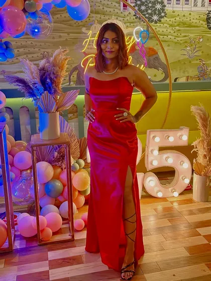 Posing with my birthday decorations. The vibrant red of the gown really pops against the colorful background.