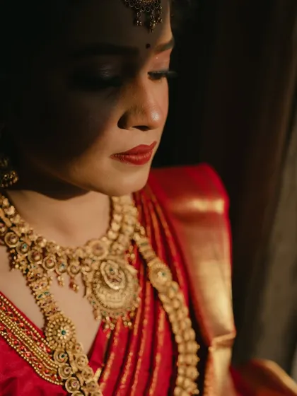 A serene and artistic shot. The play of light and shadow highlights the beautiful contours of her face and the richness of her makeup.