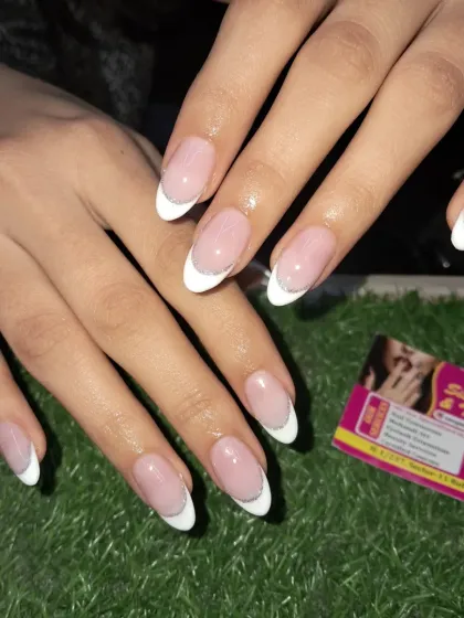 A perfect example of a classic French manicure. The clean white tips and the subtle silver glitter line create a timeless and elegant look on these almond-shaped nails.