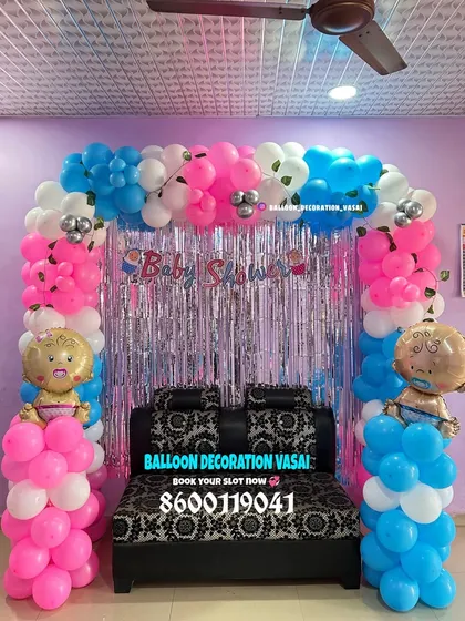 A simple yet festive baby shower decoration perfect for a home living room. The balloon arch over the sofa is accented with a shimmering silver curtain, creating a fun photo spot without taking up too much space.