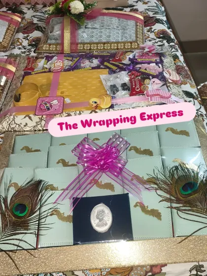 This is a newborn baby girl trousseau. It includes chocolates decorated with peacock feathers, a silver coin, and other gifts beautifully arranged on a platter.