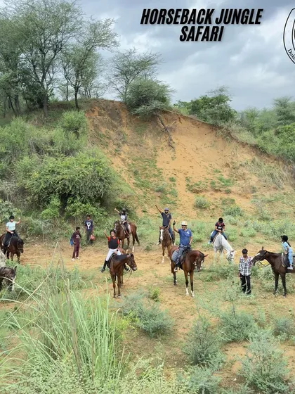 A happy group of riders pauses for a photo against a backdrop of the hilly Aravali terrain. This is a typical scene from our horseback jungle safari, showing the scale and beauty of the landscape.