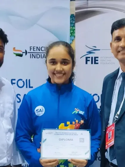 Our coaching staff proudly poses with a student after her successful performance at the FIE Foil Satellite Tournament, a key event for women's competitive fencing.
