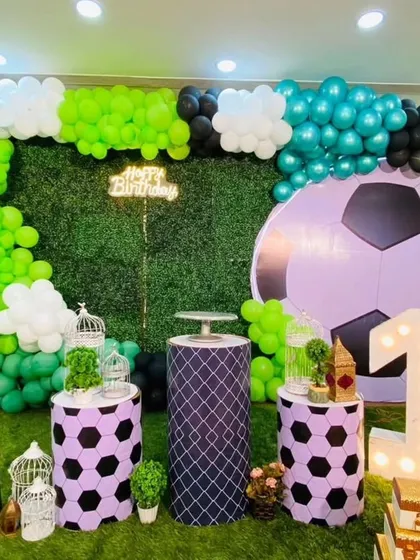 Another angle of the football-themed birthday setup. This view highlights the custom-printed plinths with a football pattern, the large light-up number '1', and the lush green artificial grass backdrop.