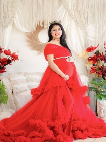 A radiant mom-to-be in a stunning red gown. This portrait in our boho studio is full of warmth and vibrant color, perfectly capturing the joy of expectancy.