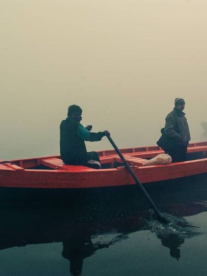 A clean, simple composition focusing on the two men rowing their boat. The reflection in the calm water adds a beautiful symmetry to this peaceful travel photograph.