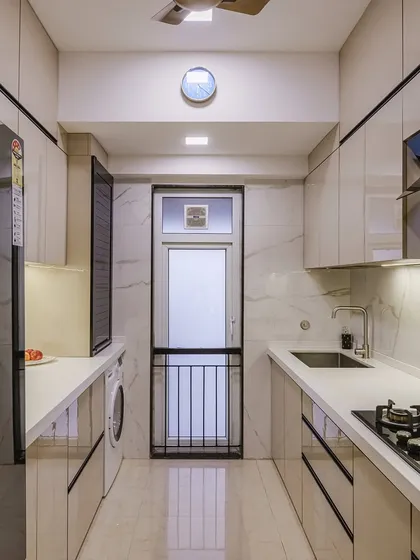 This parallel kitchen layout in beige and black offers a sleek, modern aesthetic. The glossy finish on the cabinets reflects light, making the space feel brighter and more open.