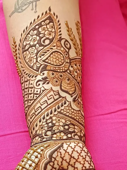 A majestic peacock design on the arm, with its feathers creating a beautiful crest.