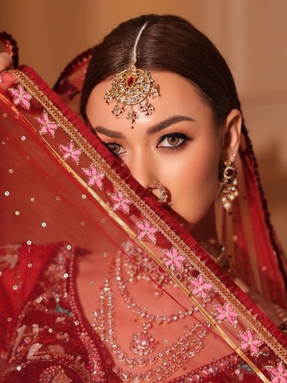 A peek-a-boo shot with the veil, focusing on the bride's eyes and the beautiful maang tikka.