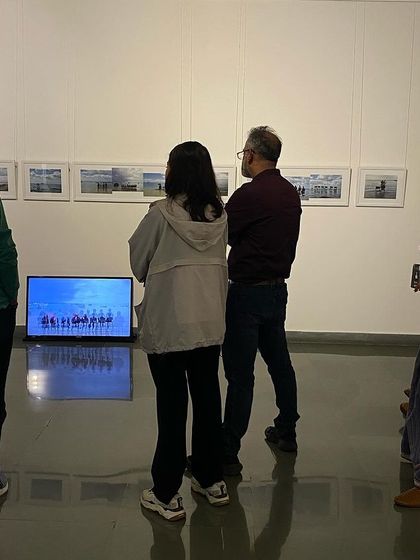 Visitors observing the 'Sea Watchers' series by Surekha, which includes both photographs and a video installation.