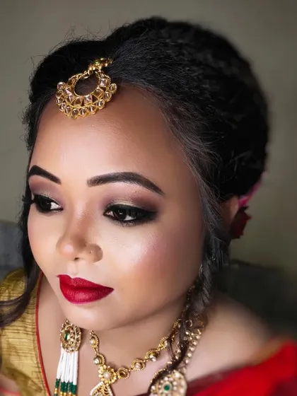 A side profile showing the elegant hair bun and the flawless finish of the makeup.