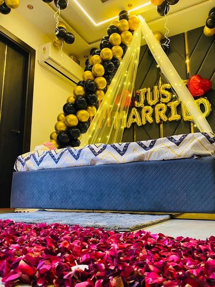 A sophisticated "Just Married" setup with a path of fresh rose petals leading to the bed. The decor uses a stylish black and gold color scheme.
