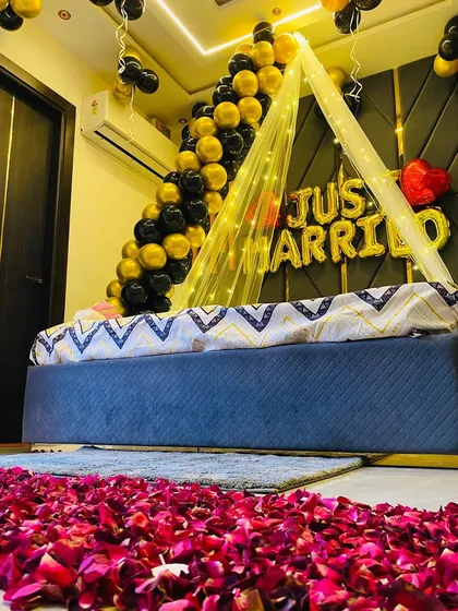 A sophisticated "Just Married" setup with a path of fresh rose petals leading to the bed. The decor uses a stylish black and gold color scheme.