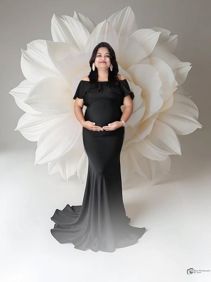 A chic and modern solo portrait in a sleek black gown. The oversized white paper flower in the background provides a beautiful and artistic contrast.