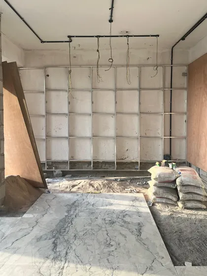 Work in progress at one of our sites, where the framework for a large shelving unit is being installed and the first marble slab is laid. This image shows the raw, foundational stage where the structural elements of our design begin to take physical form.