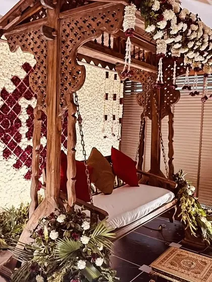 Another angle of the ornate jhoola setup, highlighting the rich textures of the carved wood against the soft floral backdrop. It’s a perfect blend of rustic charm and floral elegance.