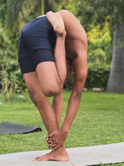 The Kunjarasana is a challenging pose that combines a deep forward bend with a twist. It’s a powerful demonstration of control.