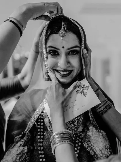 A heartwarming black and white photo of the bride getting ready, her smile shining through.