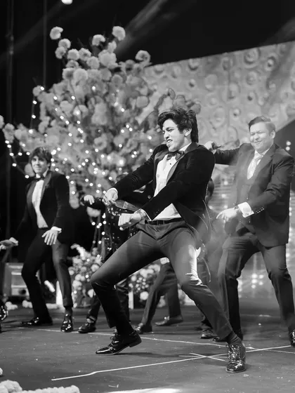 A black and white photo of the groom and his friends in a synchronized dance move, showing the power of a group performance.