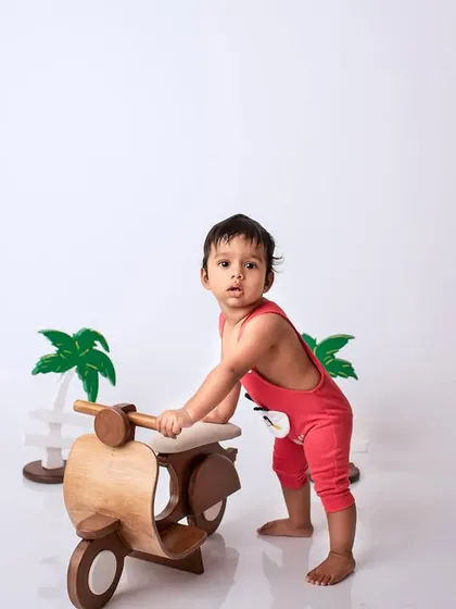 A full-length view of the baby and scooter prop against a clean white background, highlighting the playful theme of the shoot.