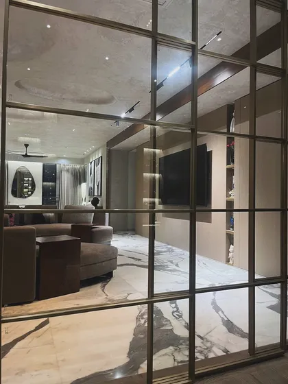 Using partitions like this gridded glass wall allows me to define spaces while maintaining an open, airy feel. It offers a glimpse into the living area, creating layers and visual interest within the home.