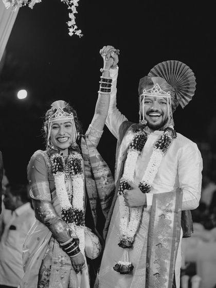 A joyful moment of celebration captured in black and white, emphasizing the couple's triumphant expressions as they raise their hands.