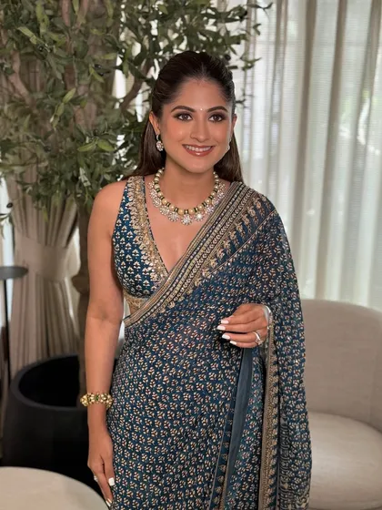 A smiling portrait of the guest, showcasing her classic makeup look with a simple bindi and soft lip color.