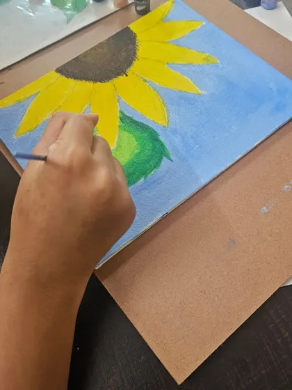 A student working on an acrylic painting of a sunflower. Our classes guide you through each step, from the initial sketch to the final brushstroke.