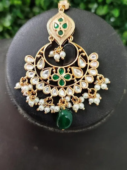 The maang tikka from this set, designed with a floral kundan motif to complete the look.