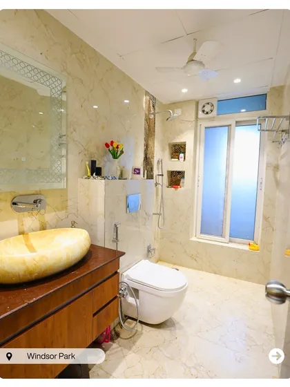 A luxurious bathroom with floor-to-ceiling marble tiles and a unique stone vessel sink. The design feels natural, earthy, and incredibly elegant.