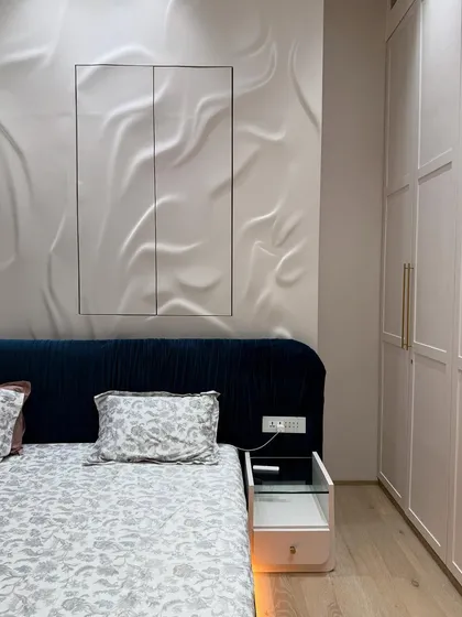 A closer look at the details: the custom bedside table with a glass top, the textured 3D wall panel, and the seamless integration of the wardrobe.