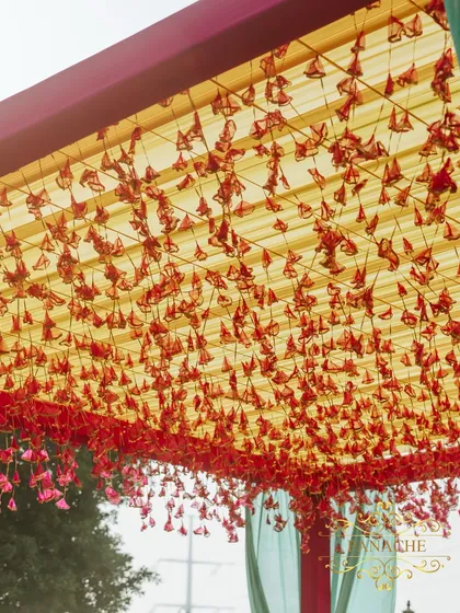 A view of the canopy ceiling, decorated with thousands of hanging red flower petals. This creates a stunning visual effect and a beautiful filtered light for the seating area below.