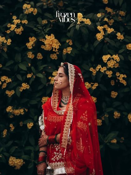 A beautiful portrait of the bride in her traditional red attire against a backdrop of yellow flowers. The color contrast makes this image pop.